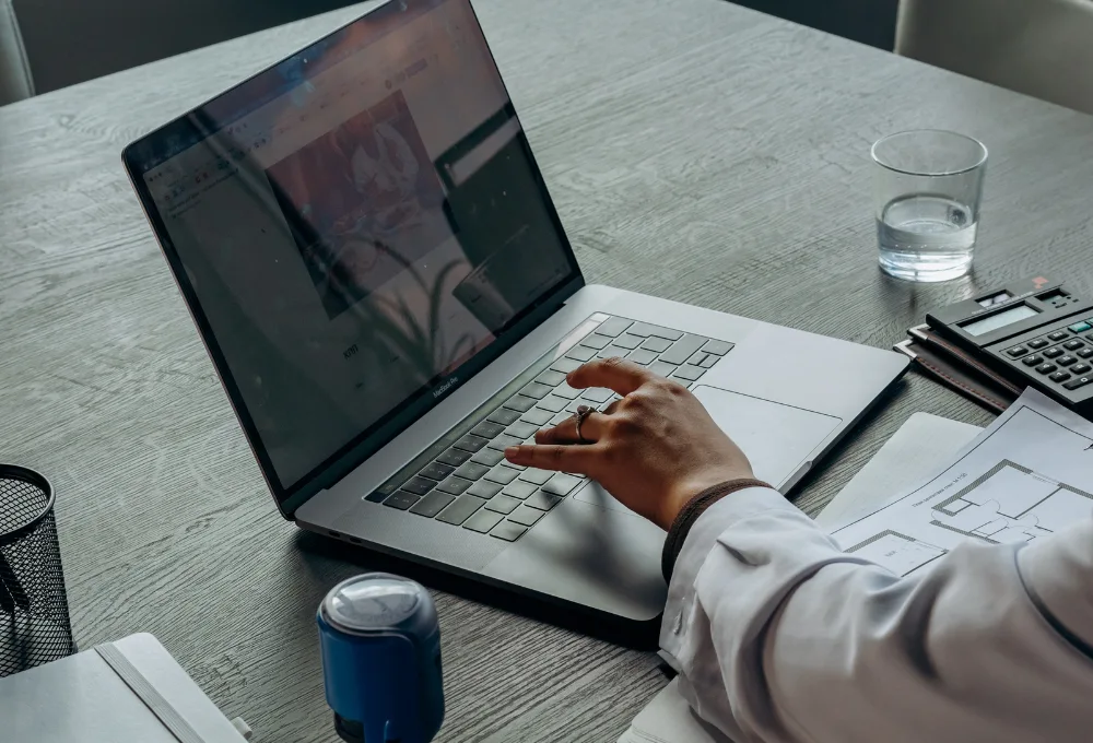 Hand typing on laptop in workspace