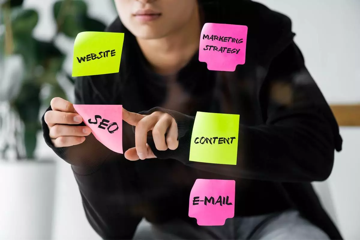 SEO manager placing sticky notes for website, content, marketing strategy, and email planning.