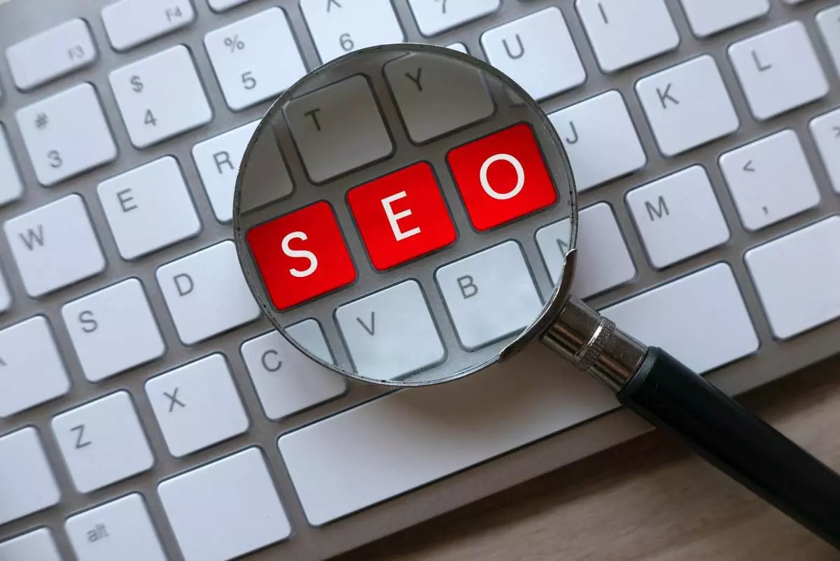Magnifying glass highlighting the letters SEO on a computer keyboard, representing SEO services.