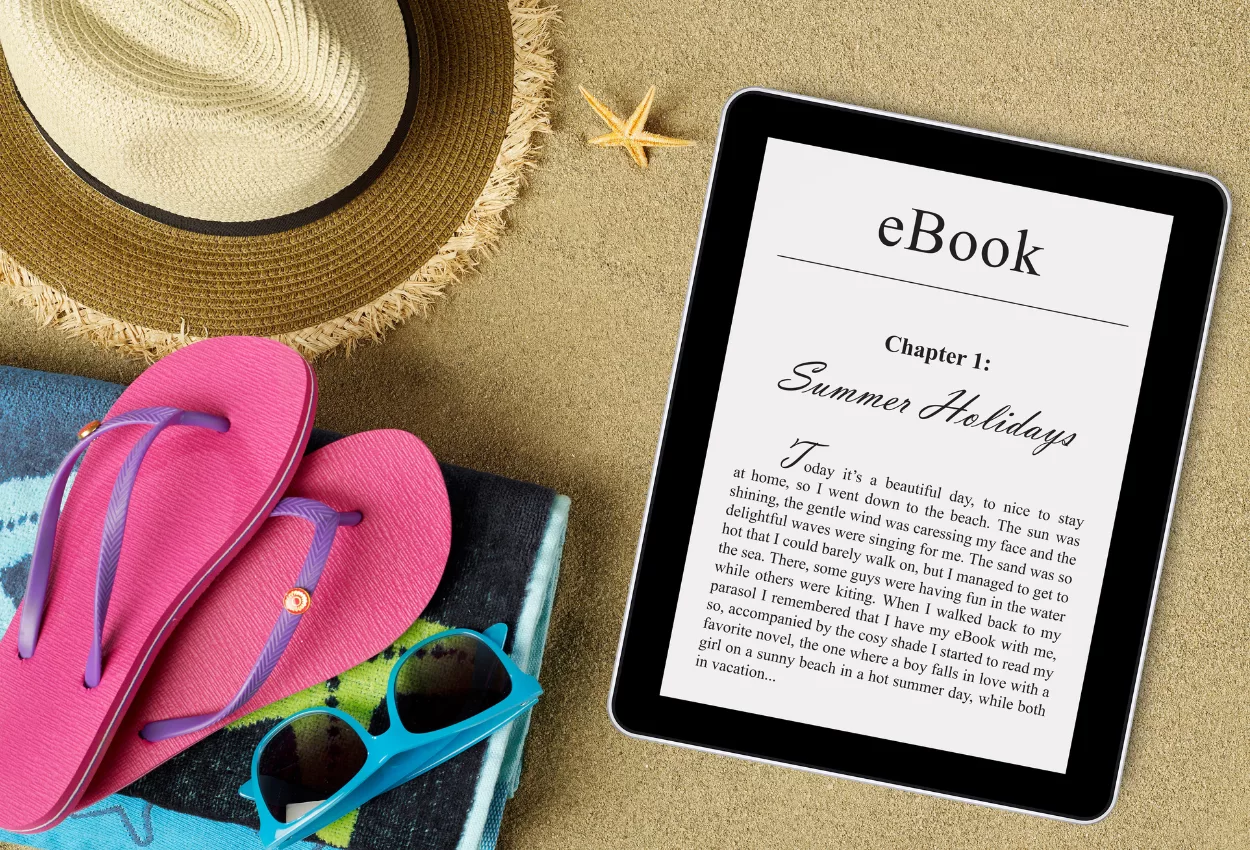 Beach setup with tablet showing e-book cover design featuring 'Summer Holidays' chapter.