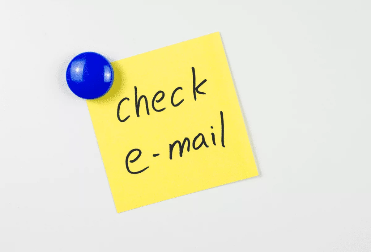 Reminder to check e-mail written on a yellow sticky note with a blue magnet