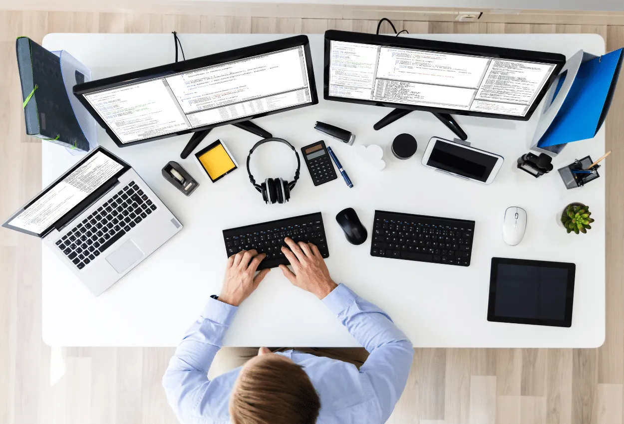 Software developer coding on multiple monitors at desk