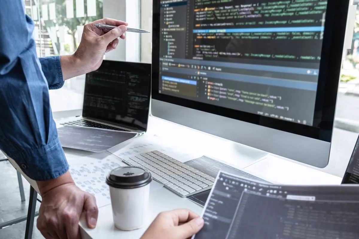 Team of developers working on a software development contract with code on the screens.